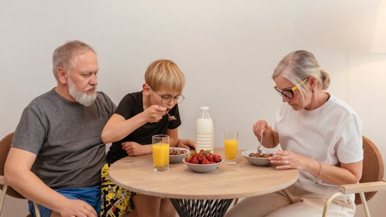 A family of three enjoying breakfast around a wooden table at home.